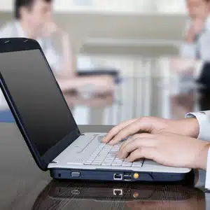 Businessperson typing on laptop, preparing examples of notarized documents for online submission and storage