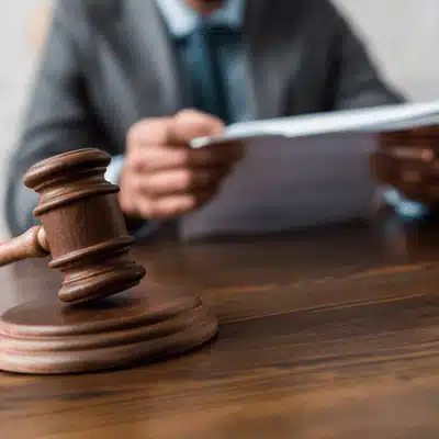 A judge in a suit reviews legal documents with a wooden gavel on the table