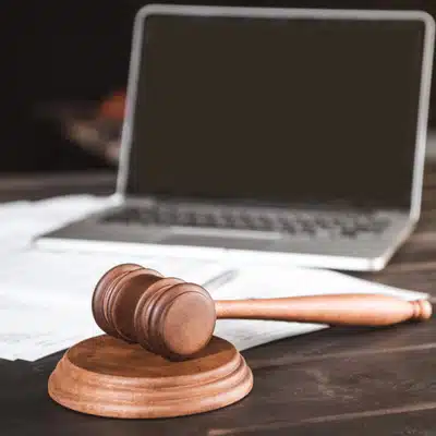 Wooden gavel placed beside a laptop on a legal desk illustrates trial technology services usage