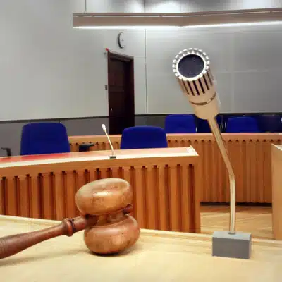 A wooden gavel and microphone positioned on a desk inside an empty courtroom before proceedings