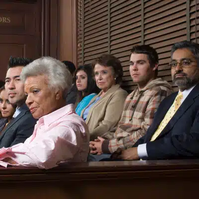 Diverse jurors watch testimony attentively, evaluating evidence supported by courtroom visuals during ongoing trial proceedings