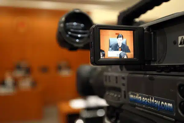 A courtroom camera captures a judge speaking during a legal proceeding in a courtroom setting