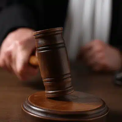 A judge’s hand brings down a wooden gavel in a courtroom during a legal decision
