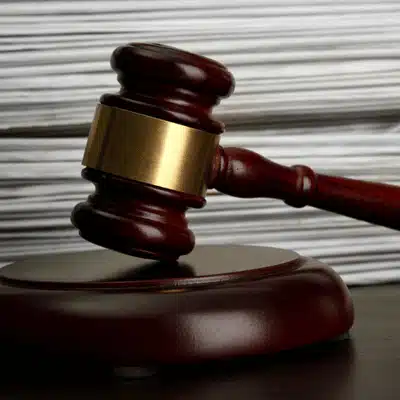 Wooden gavel resting on block with stacked documents in background, representing law and legal authority