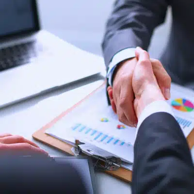 Lawyer and client handshake over financial charts, confirming agreement on trial graphics strategy and timeline