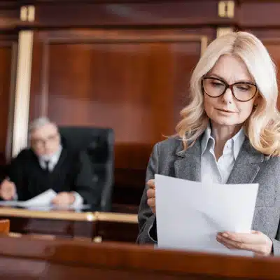 Attorney reviews paperwork in courtroom while judge listens, highlighting the court reporter role in proceedings