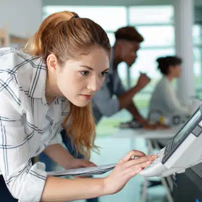 Focused employee uses copier touchscreen to select settings and start scan, ensuring correct document output