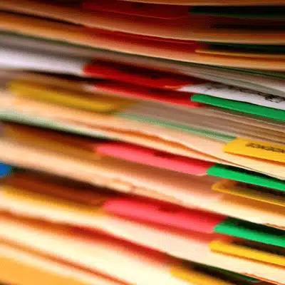 Stack of multicolored file folders with labeled tabs, illustrating organized paperwork awaiting detailed review today