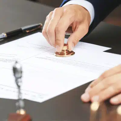 Notary presses metal seal onto document, validating paperwork with embossed certification during legal process today