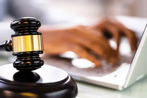 Photo shows judge’s gavel near hands typing on laptop, illustrating electronic trial support services work