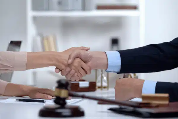 Two professionals shake hands at legal desk, gavel nearby, case guided by litigation support advisors