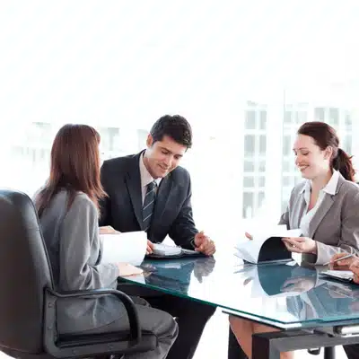 Attorneys review documents at glass table, planning case steps inside Office war room setting