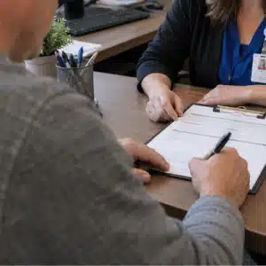 A patient signs a medical release form with a healthcare administrator as part of the process to subpoena medical records